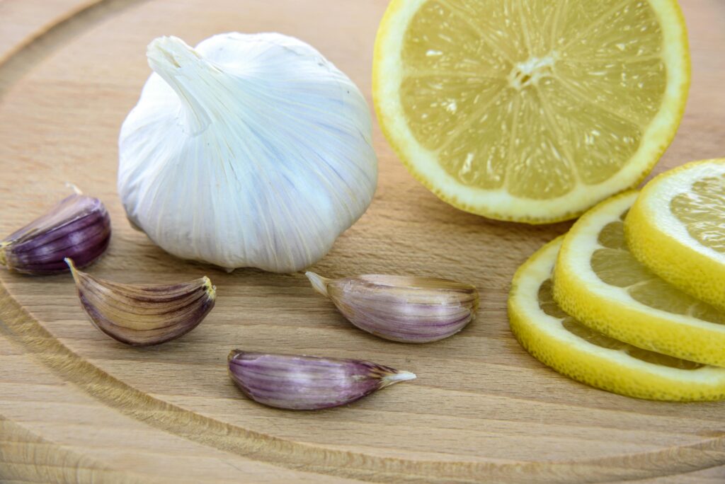 Close-up of fresh garlic and lemon slices on a wooden board, ideal for healthy cooking.